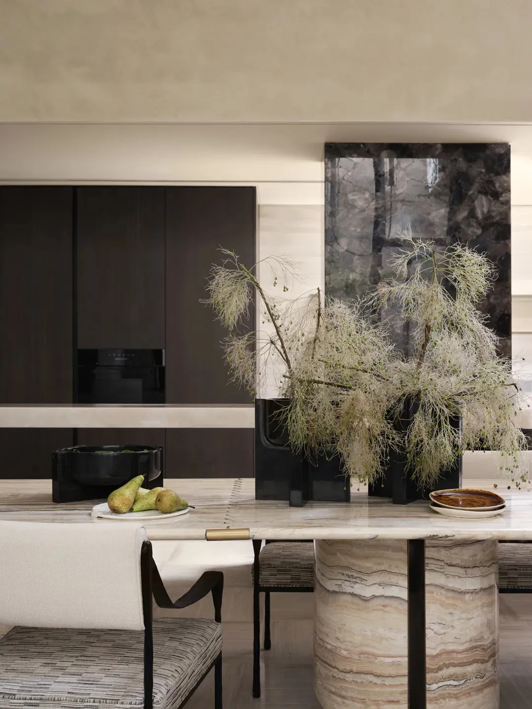 A modern living and dining space featuring marble and concrete materials, with a decorative plant arrangement.