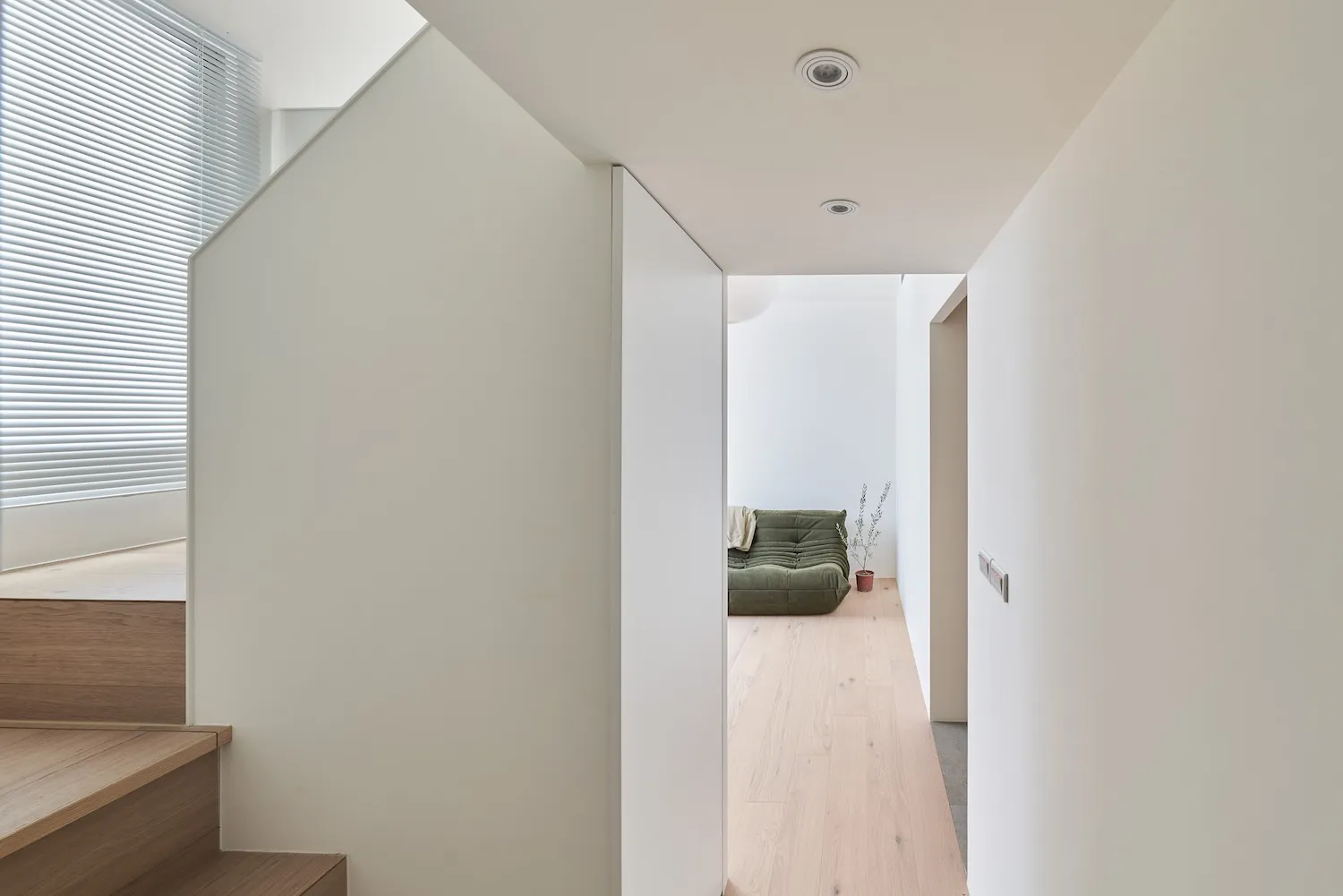 Modern minimalist hallway with wooden stairs, glass wall, and concrete floor.