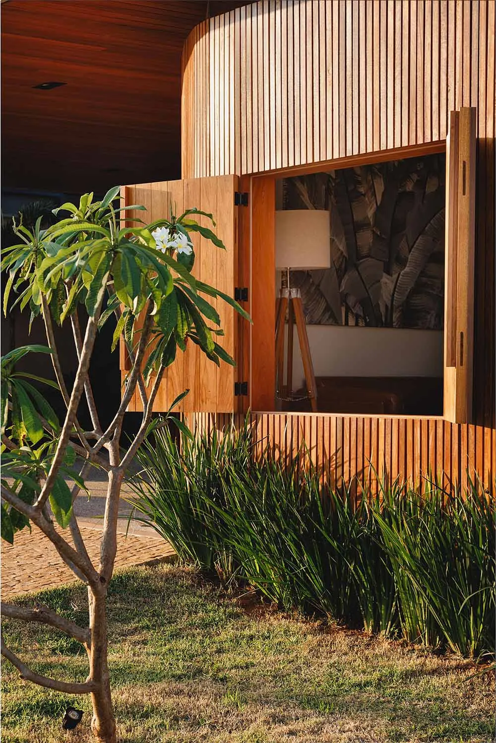 Modern residential facade with wooden slat exterior and greenery around.