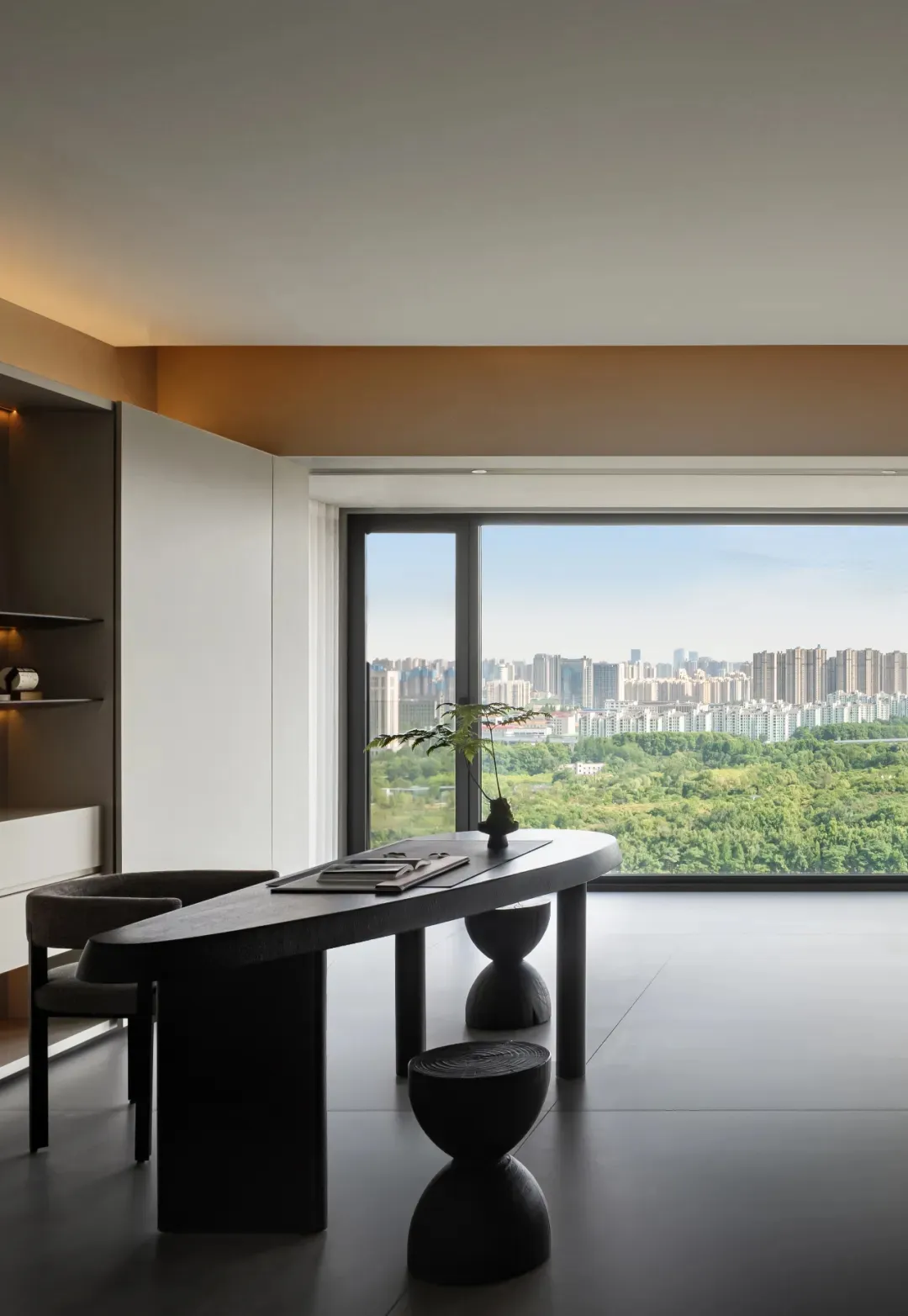 A minimalist office space with a modern, wooden desk and a panoramic window overlooking a cityscape.