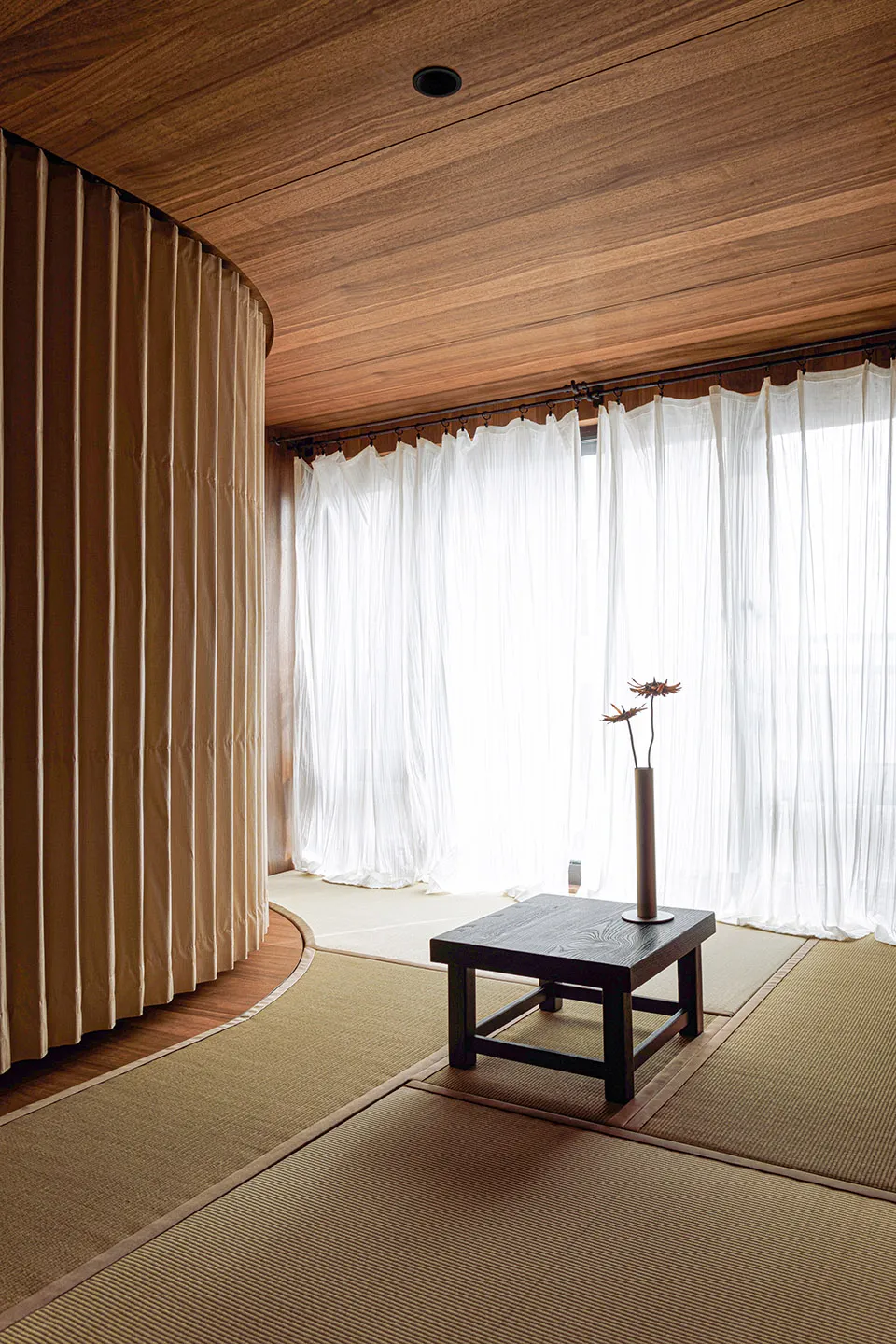 A minimalist room interior with bamboo mats, wood paneling, and fabric curtains.