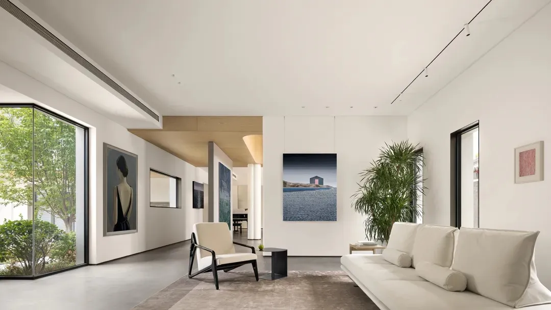 Minimalist living room with concrete tiles, white sofa, armchair, and framed artwork.