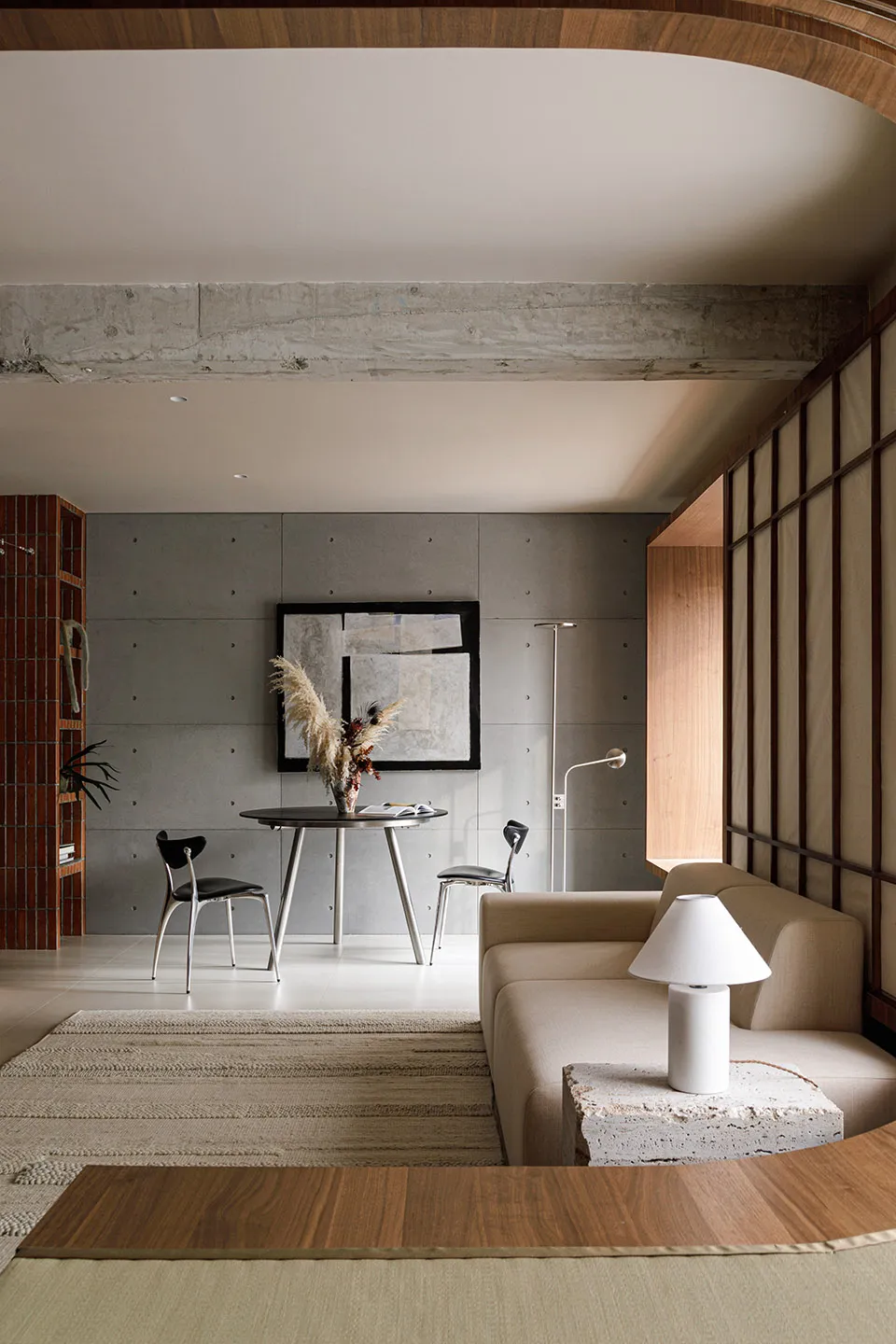 Minimalist living room featuring a concrete accent wall, wooden furniture, and woven decor elements
