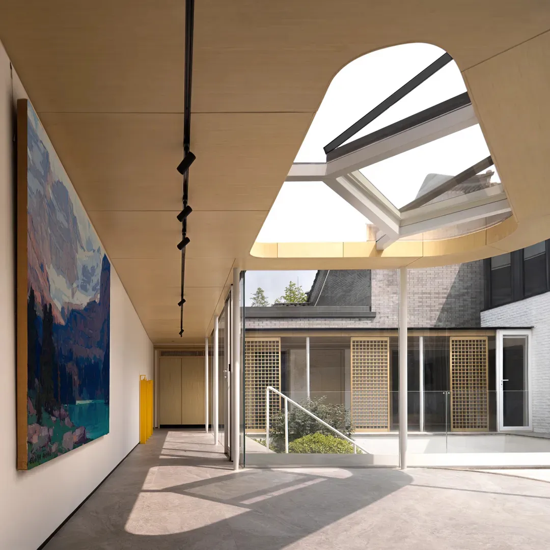 Modern art gallery with wood beams, glass walls, and large abstract painting.