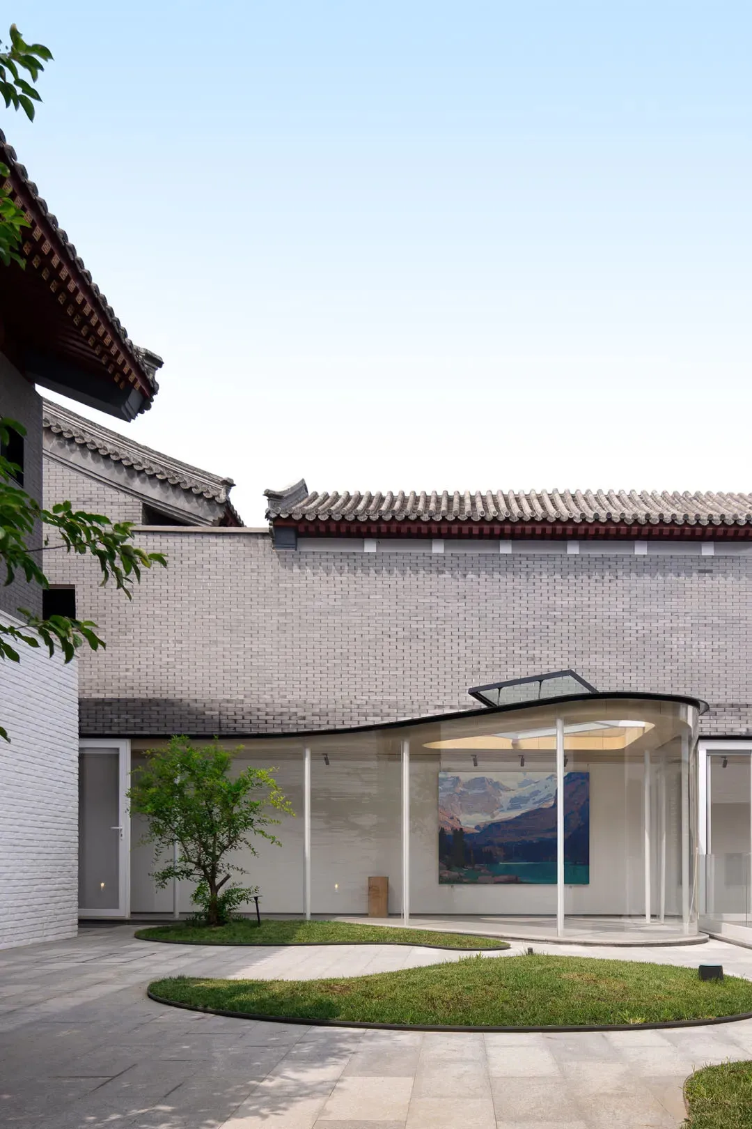Modern building exterior with white brick walls and gray tiled roof.