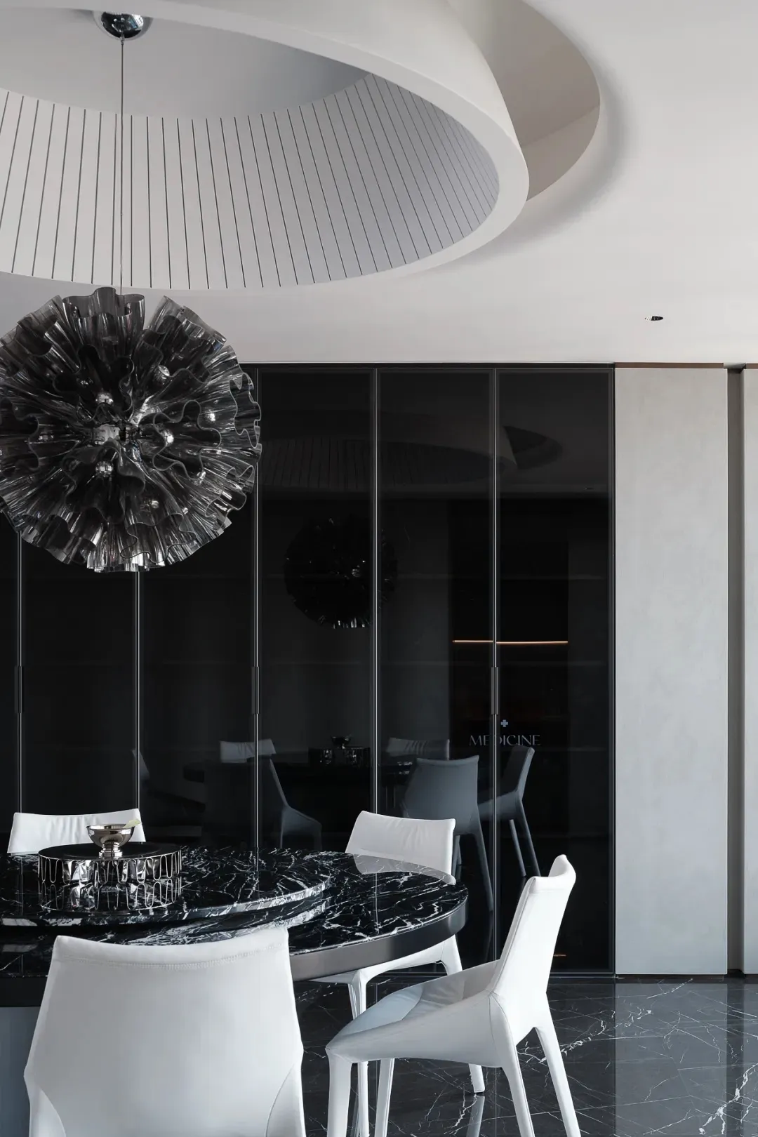 Contemporary dining area featuring a black marble table and white chairs.