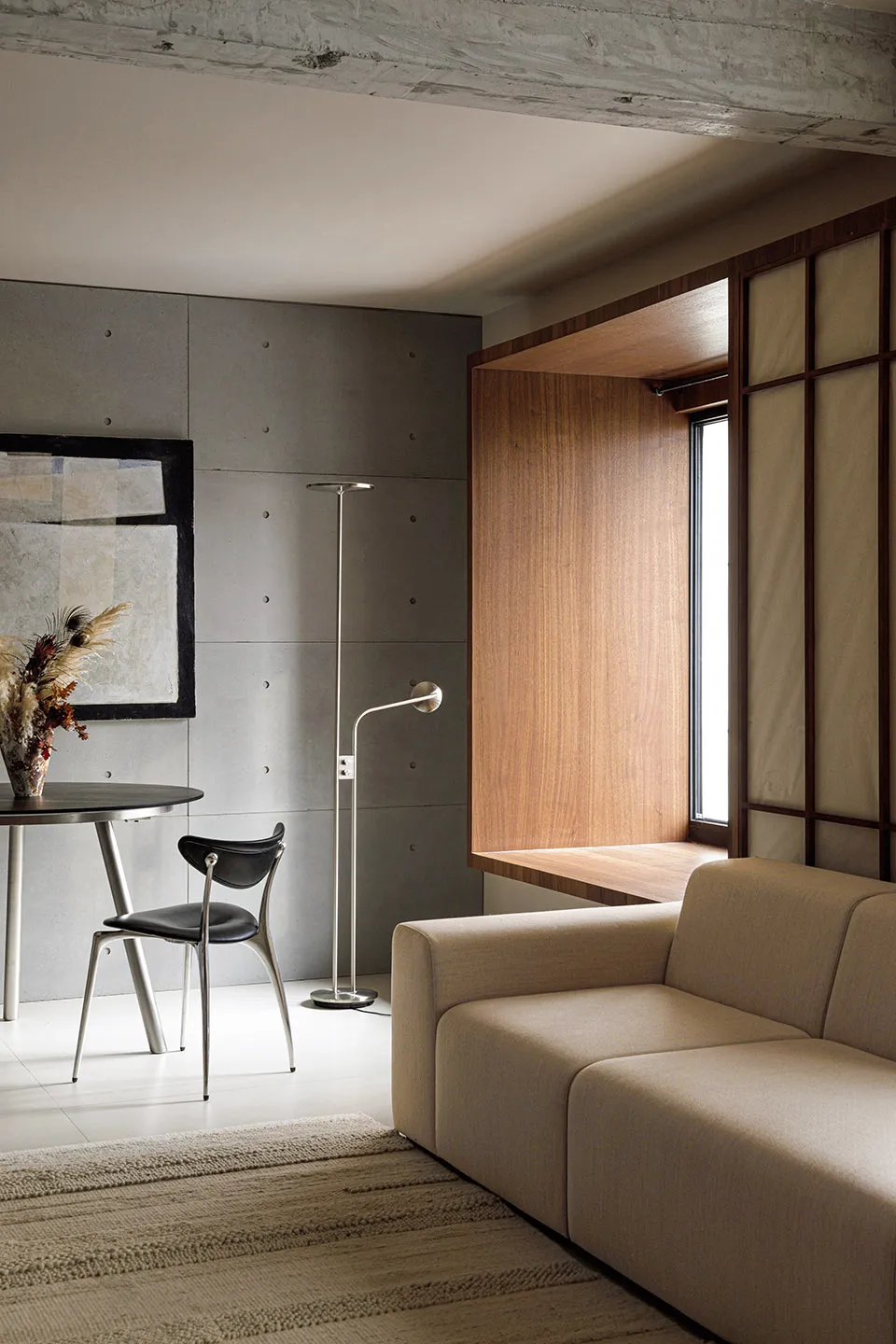 A modern living room featuring a concrete wall and a wooden window bench.