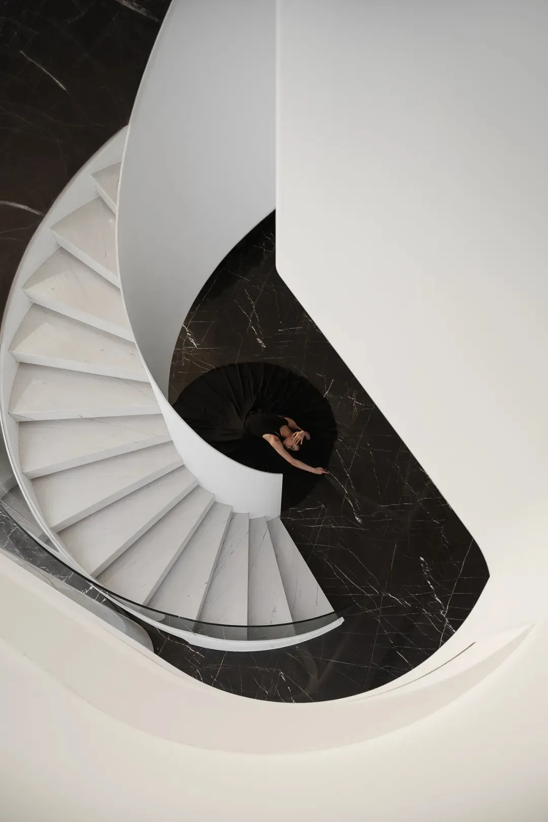 A modern staircase featuring white marble steps and black marble floor.