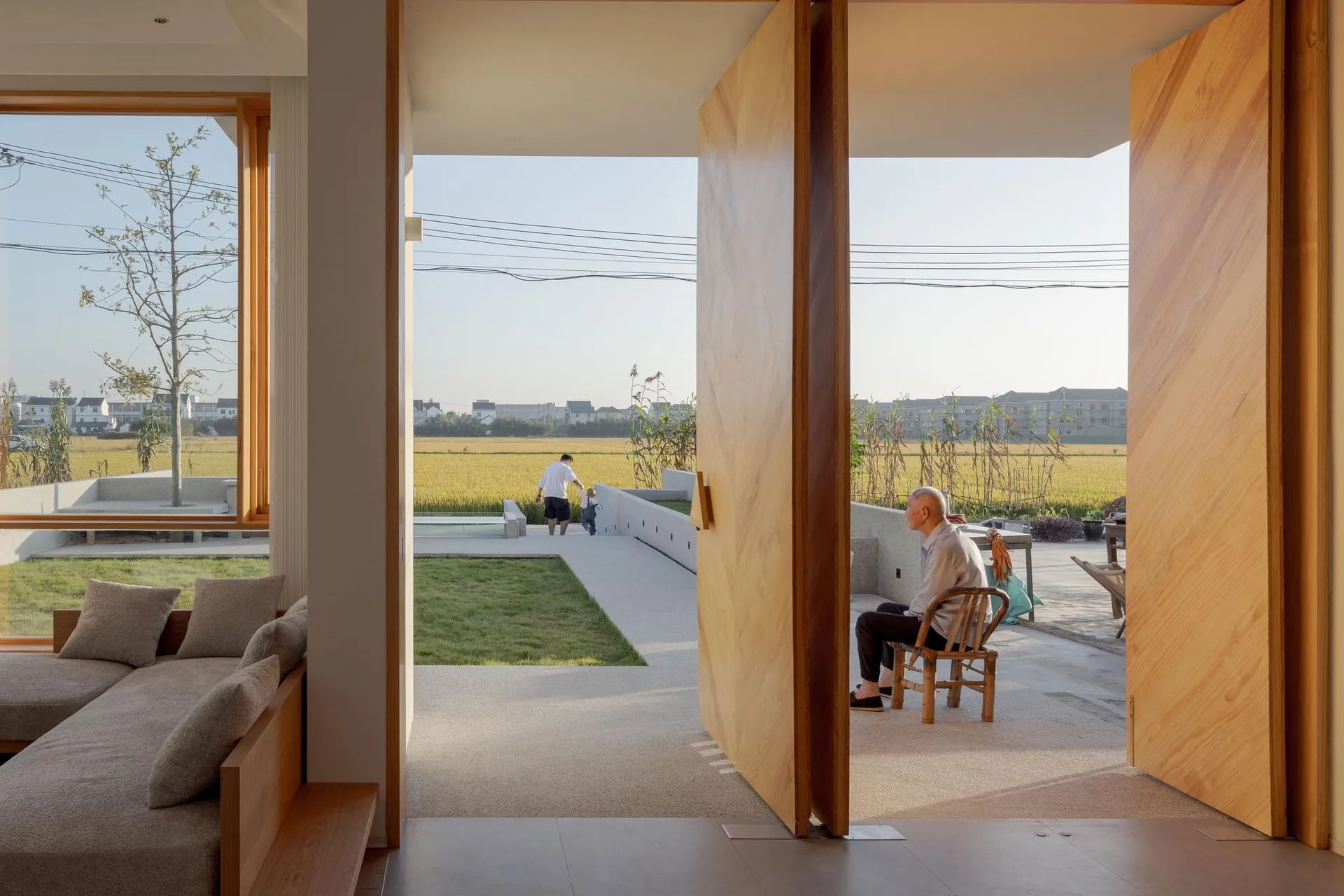 A minimalist residential space with an open-plan layout featuring a mix of wood, concrete, and glass materials.