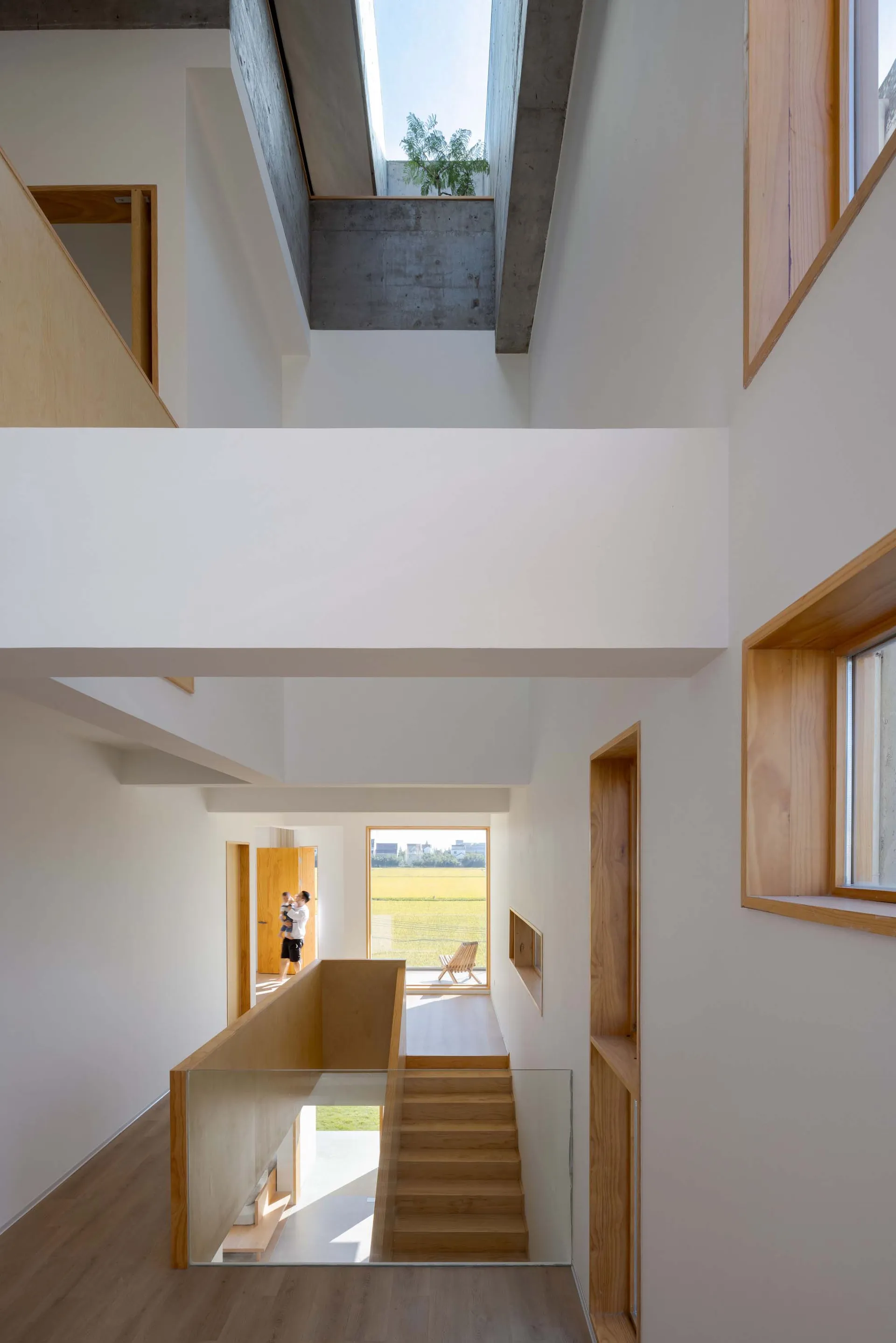 現代室內空間擁有白牆、木質樓梯、混凝土天花板,以及可眺望綠色田野的大窗。