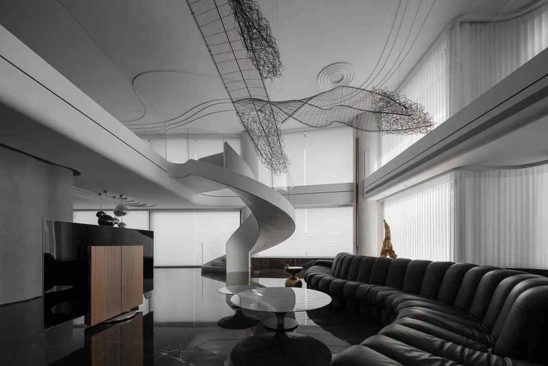 Modern living room with black leather seating, metal accents, and white marble flooring.