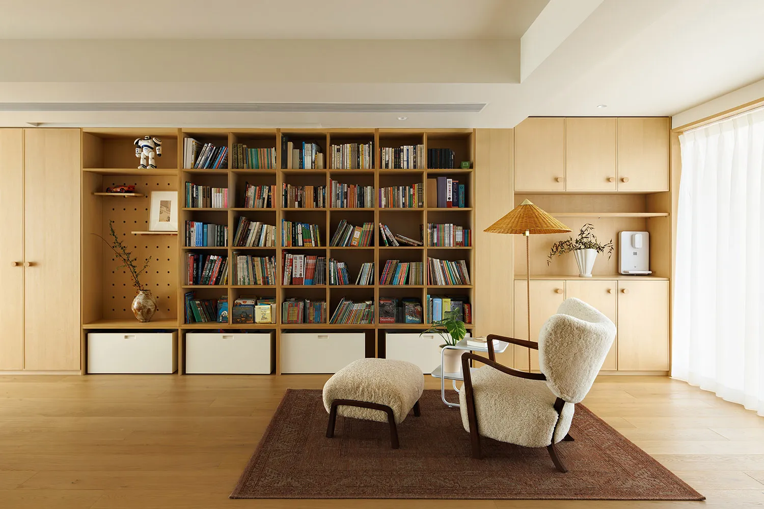 Modern library room with wooden shelves filled with books and a cozy seating area.