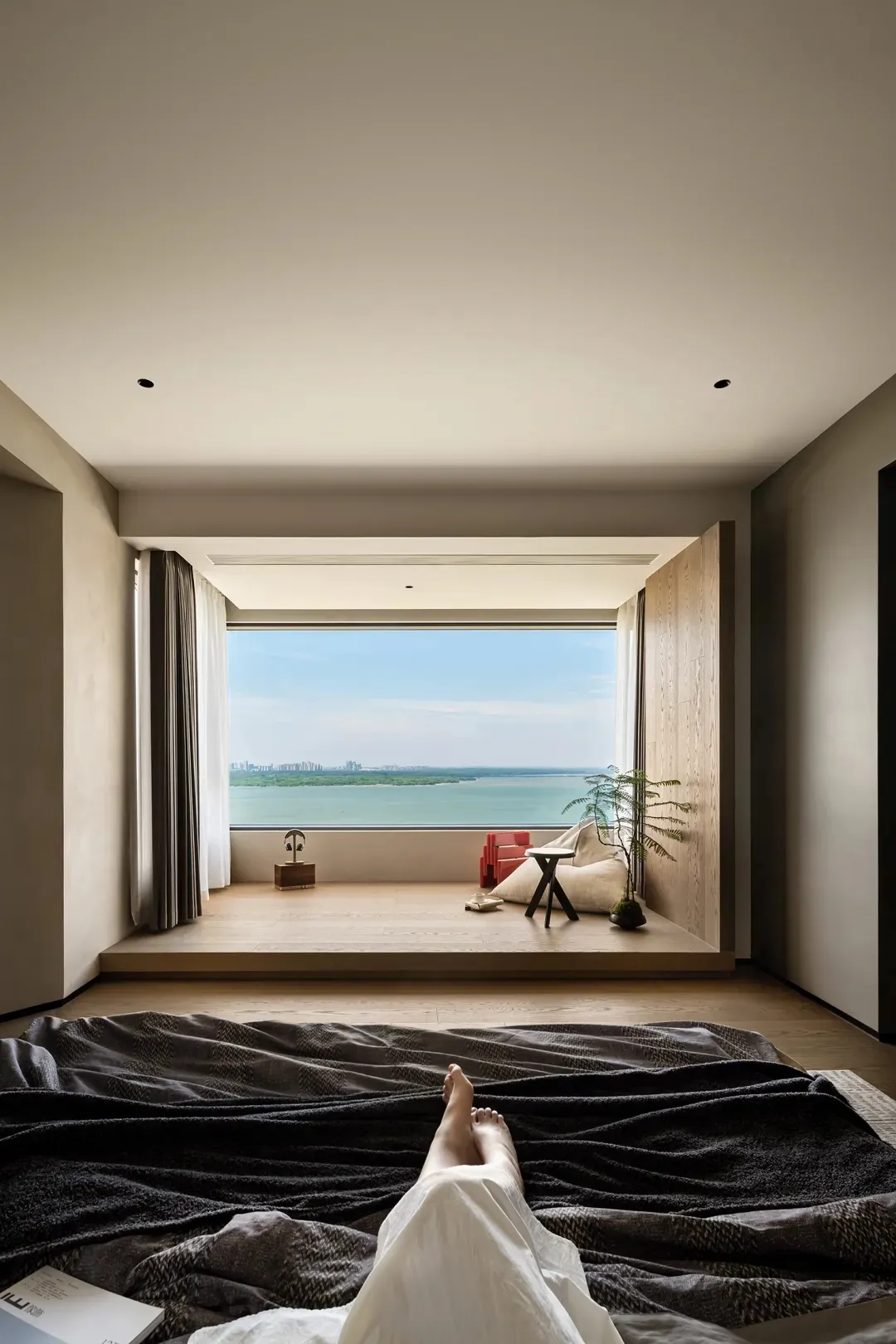 A modern living room featuring concrete flooring and wooden walls, with a minimalist design and a view of a serene lake.