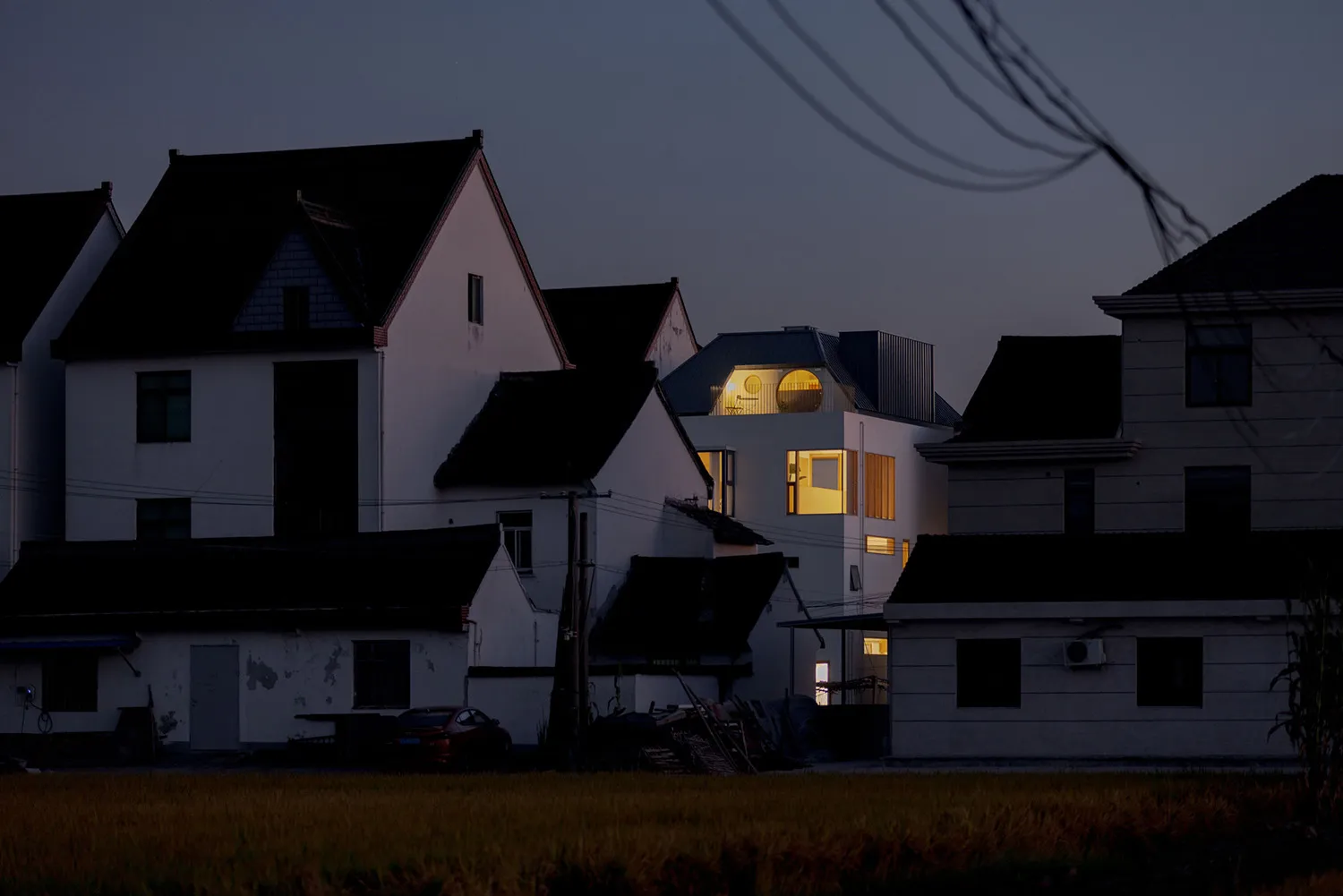 A modern, minimalist country home with concrete and stucco exterior materials during twilight.