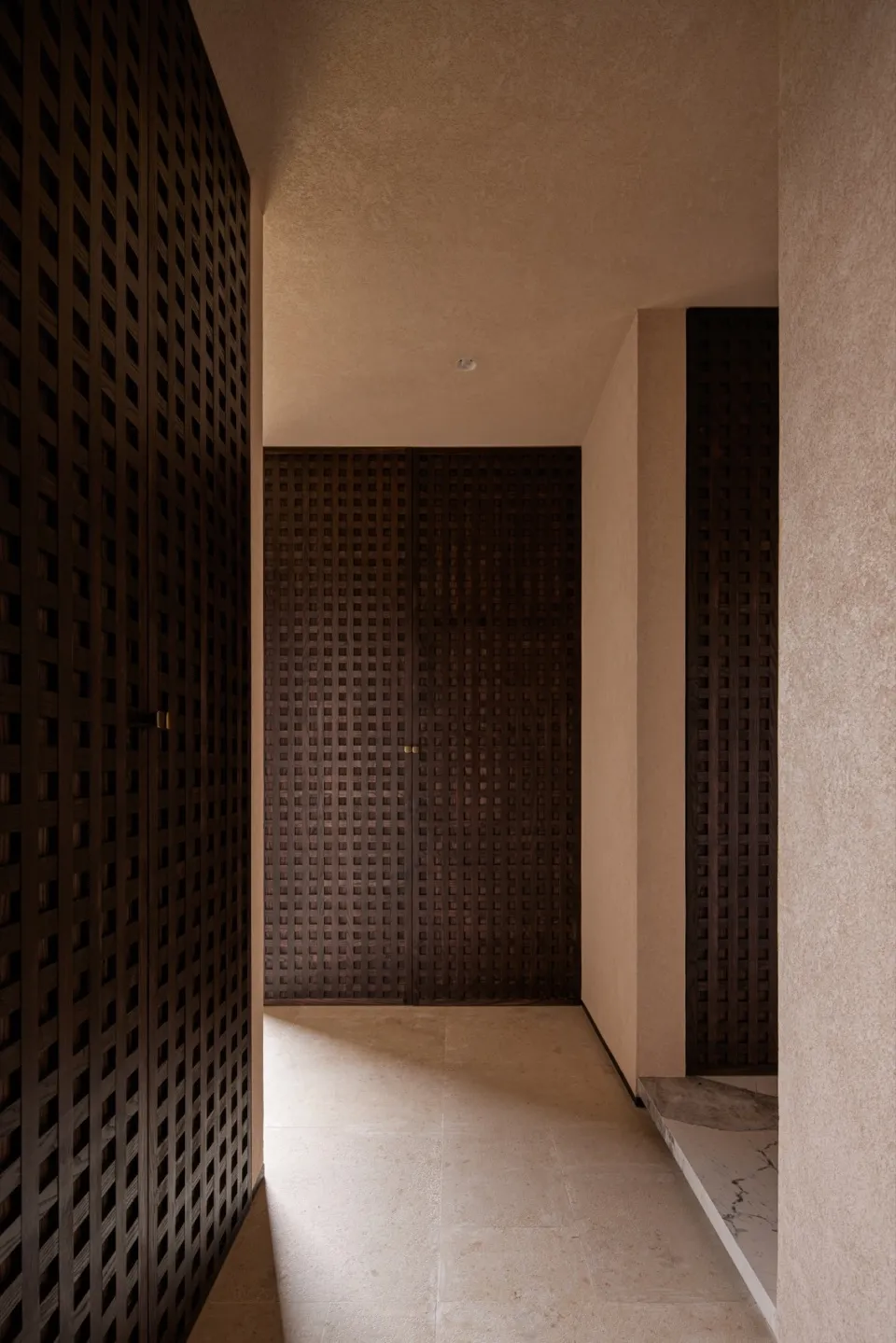 Modern corridor featuring stone paneling and lattice doors