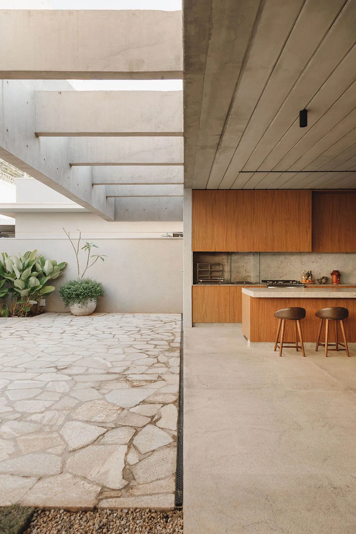 A modern patio featuring concrete flooring and a concrete staircase with greenery in the background.