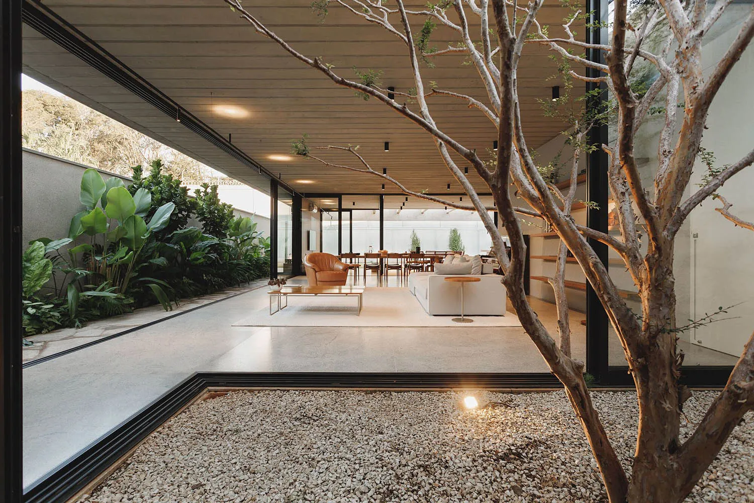 Modern villa interior with a minimalist design featuring concrete and wood materials, expansive glass walls, and natural land