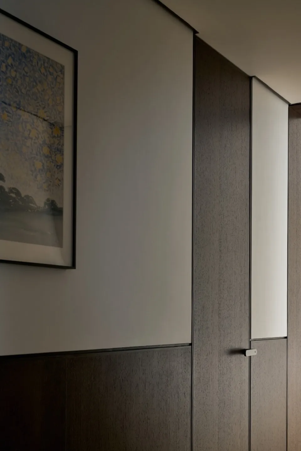 Minimalist interior design featuring wooden cabinets against a white wall.