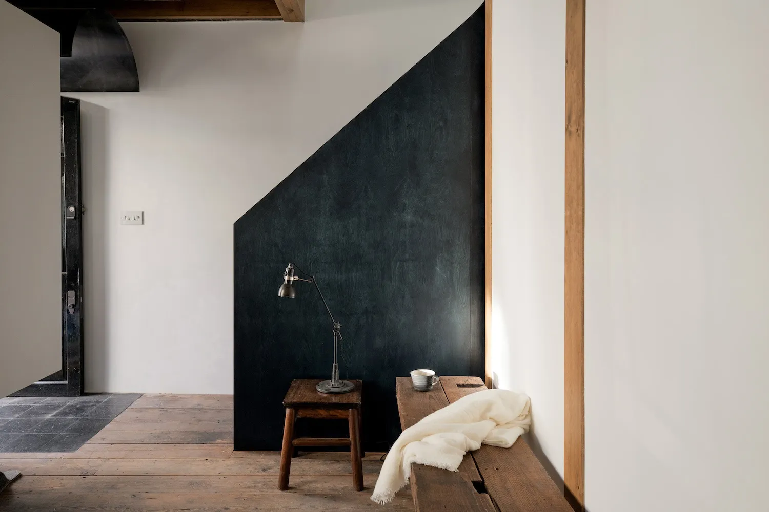 Light-flooded room with sleek, stylish elements, featuring a wooden floor and black accent wall.