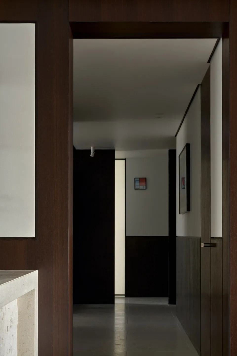 A modern interior corridor featuring dark wood finishes and a minimalist design.