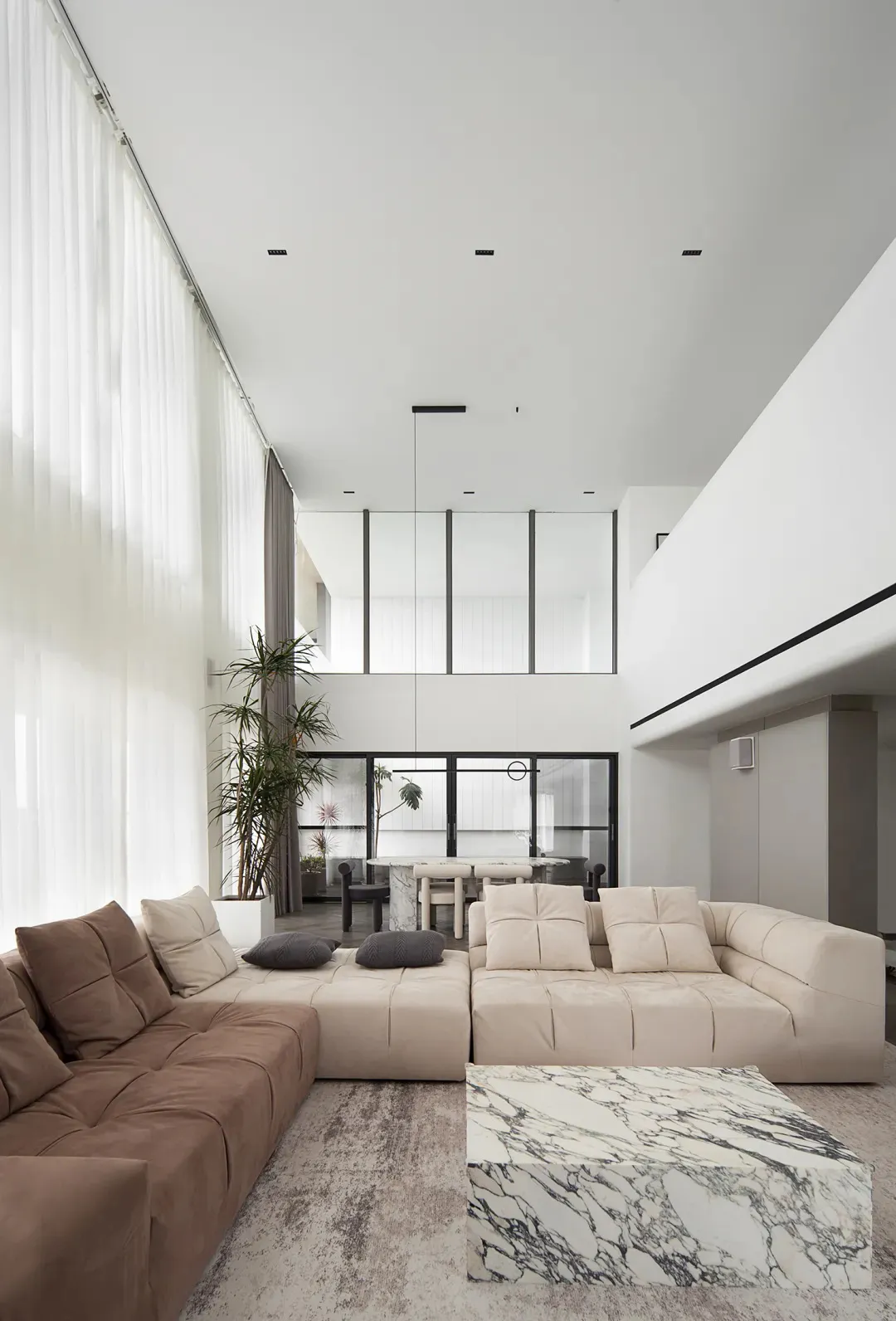 Modern minimalist living room with leather sofas, marble coffee table, and glass windows