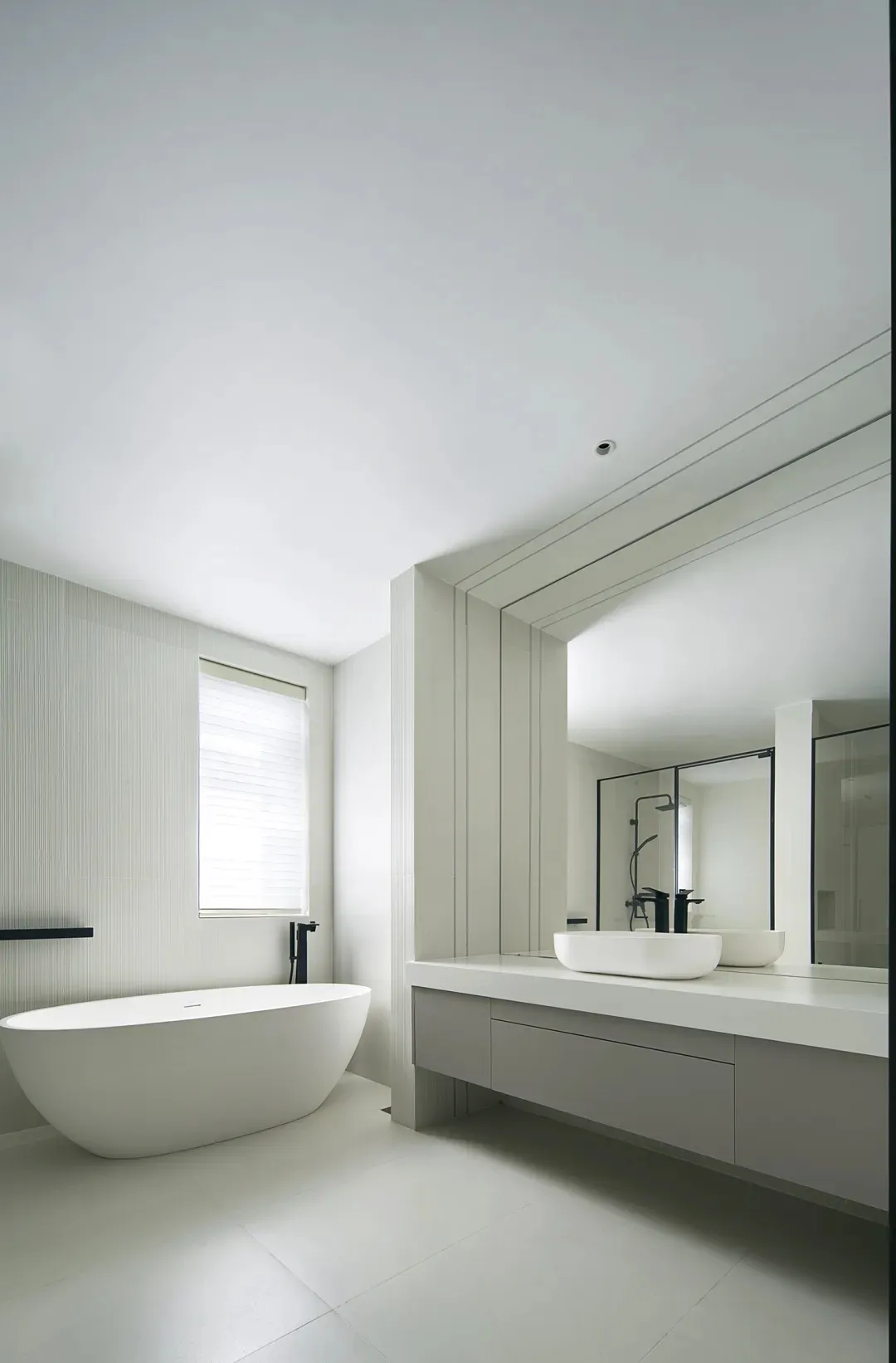 Modern white bathroom with a freestanding bathtub and a floating vanity with a large mirror.