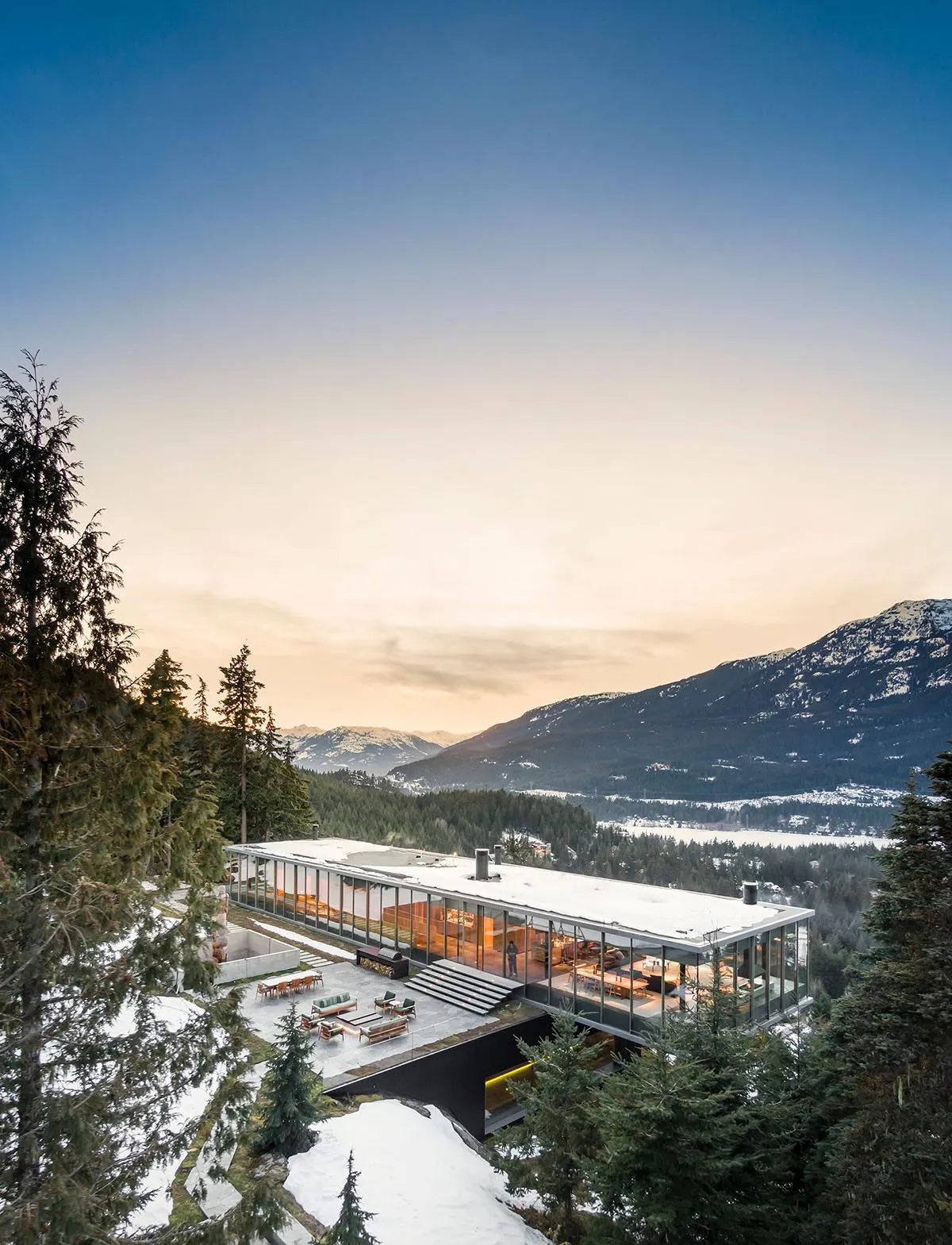 一座現代住宅建築,擁有大型玻璃牆,可俯瞰雪山景色。