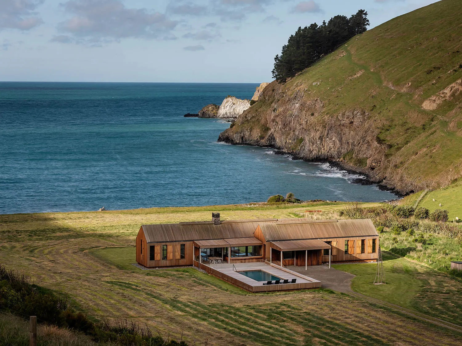 A modern house with a timber exterior overlooking the sea.