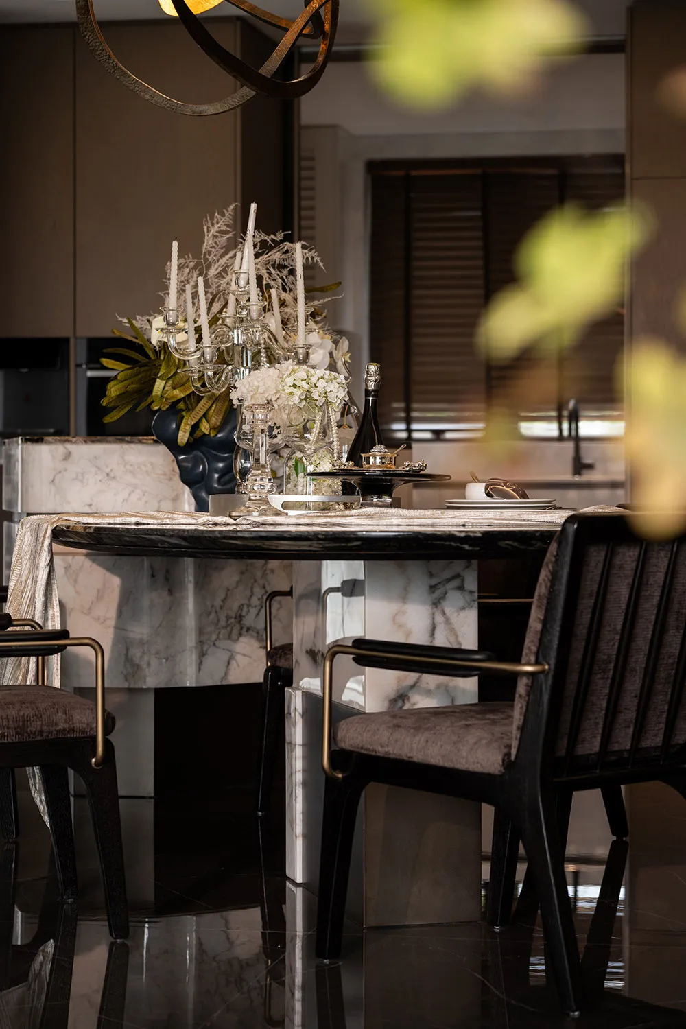 Modern dining room with marble materials, featuring a dining table, chairs, and decorative table setting with candles and flo