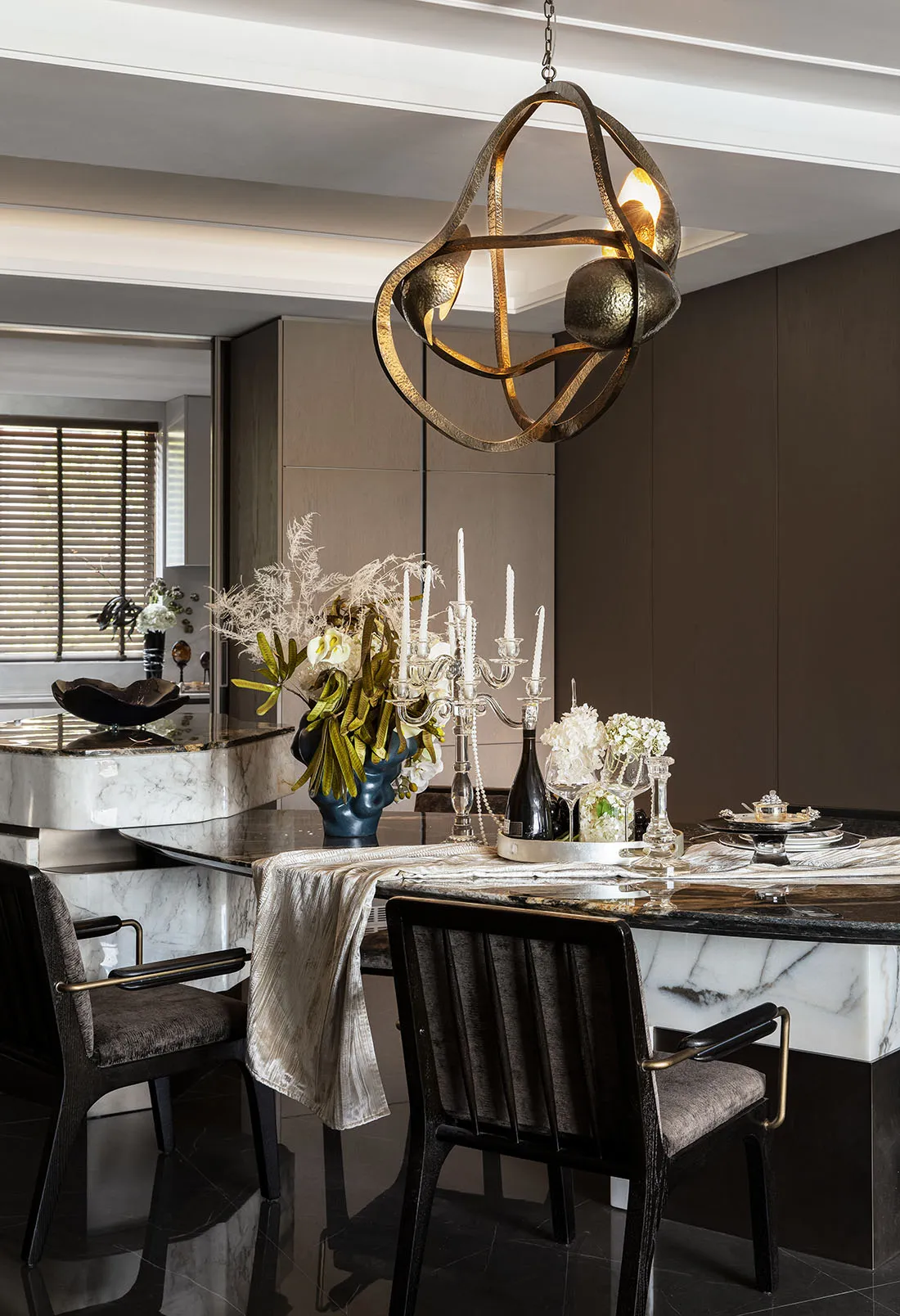 Modern dining room featuring a marble dining table with metal chairs and a contemporary light fixture.