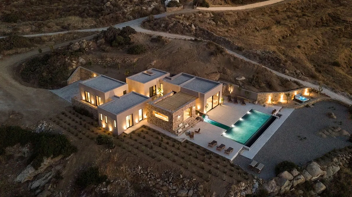 Aerial view of a modern residential exterior featuring concrete, glass, and stone materials.