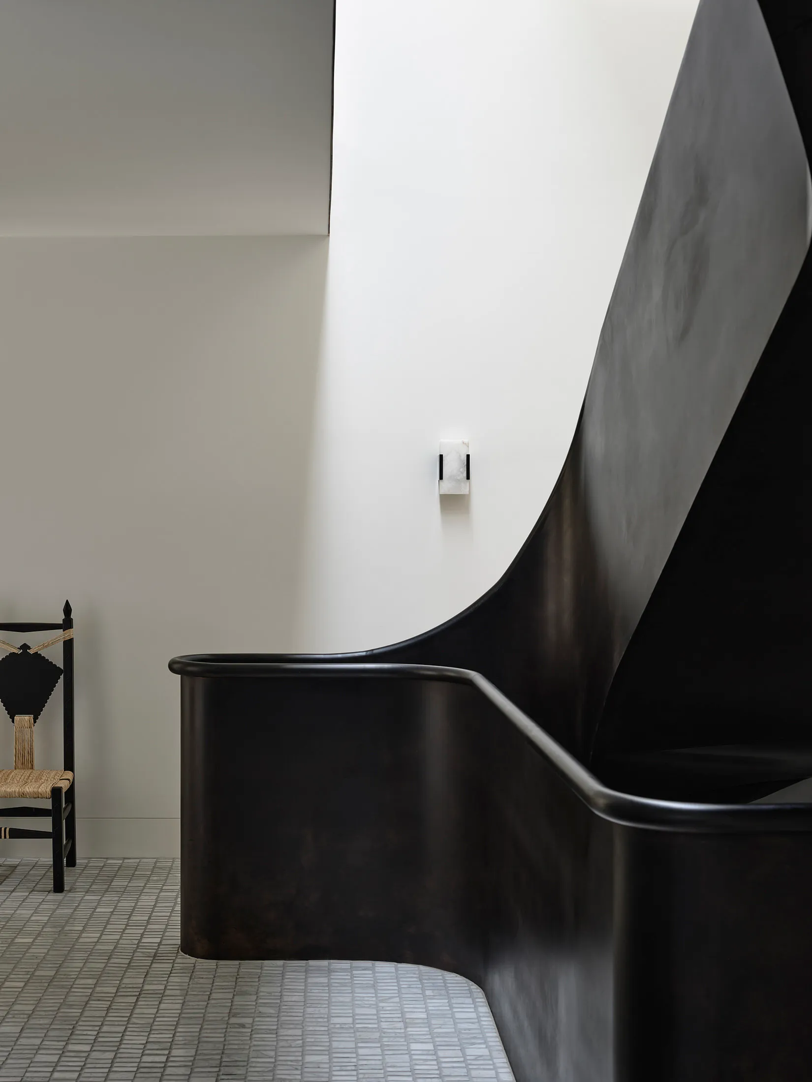A modern, black metal staircase with curved railings.