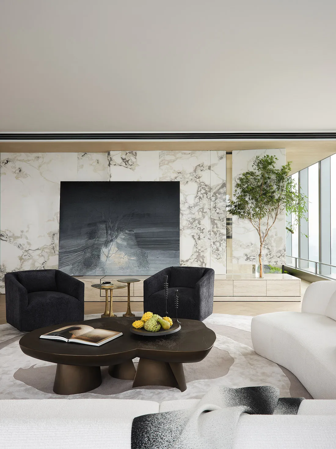 A modern living room featuring a textured marble and concrete wall, with dark and white furniture and a large abstract painti