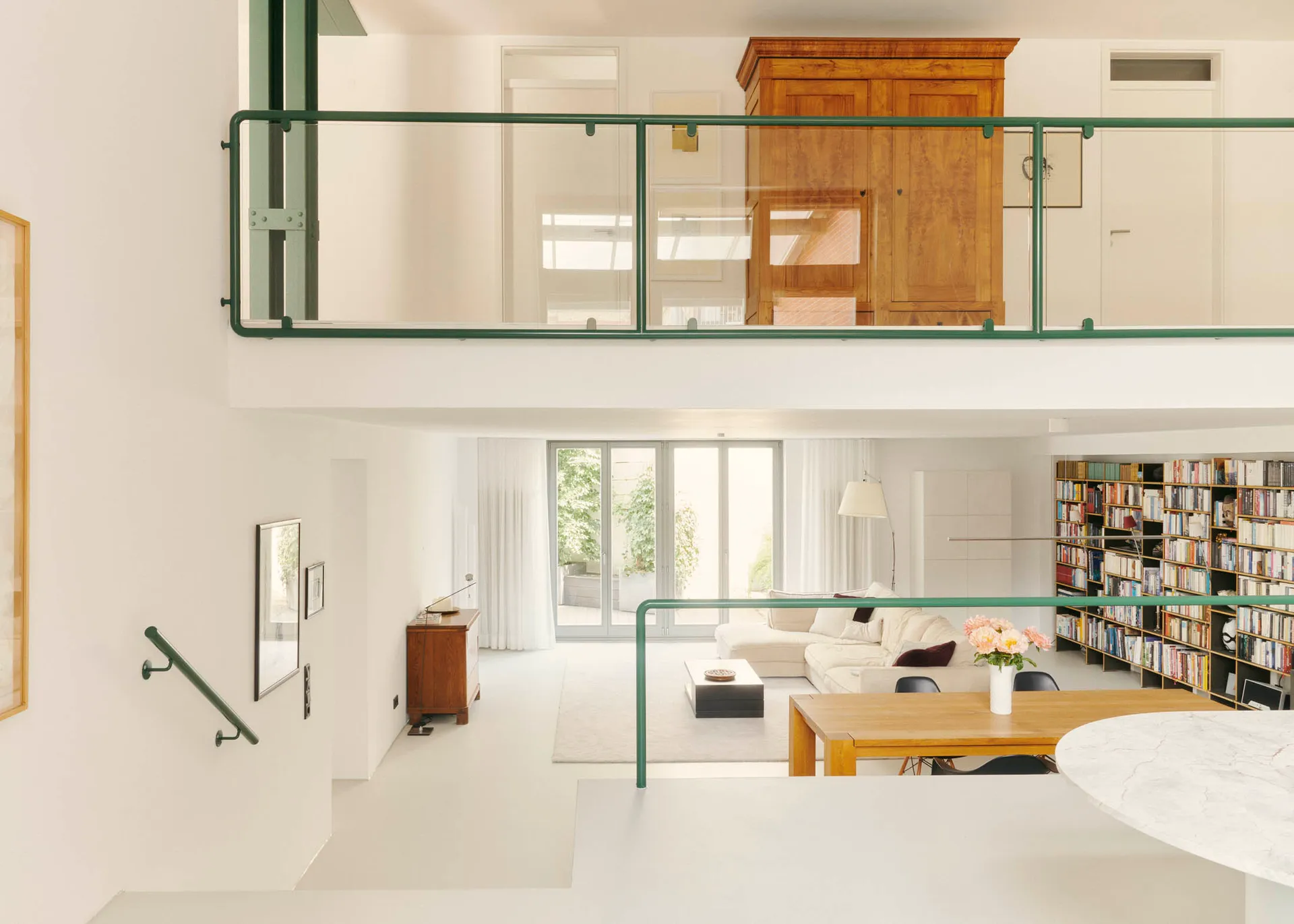 A modern minimalist living room with white concrete and wood elements, including a white sofa, a wooden coffee table, and a w