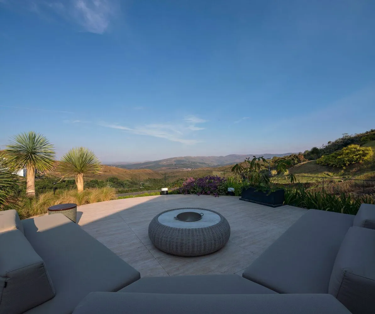 Outdoor living space featuring a wooden deck with lounge seating, a circular fire pit, and views of rolling hills and distant