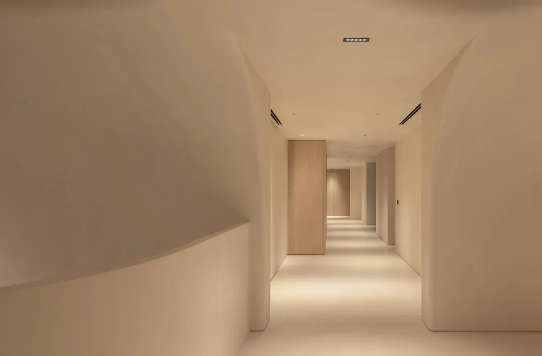 A minimalist corridor with concrete walls and floors, featuring clean lines and simple design elements.