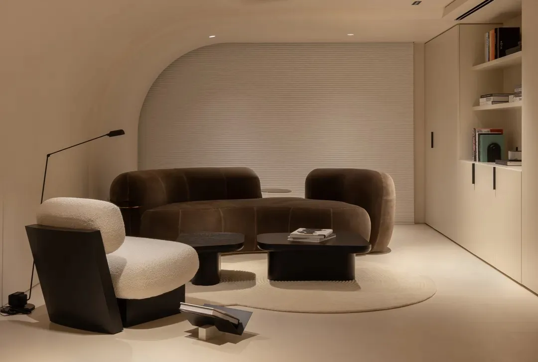 Modern living room with a brown velvet couch and a circular coffee table on a circular rug.
