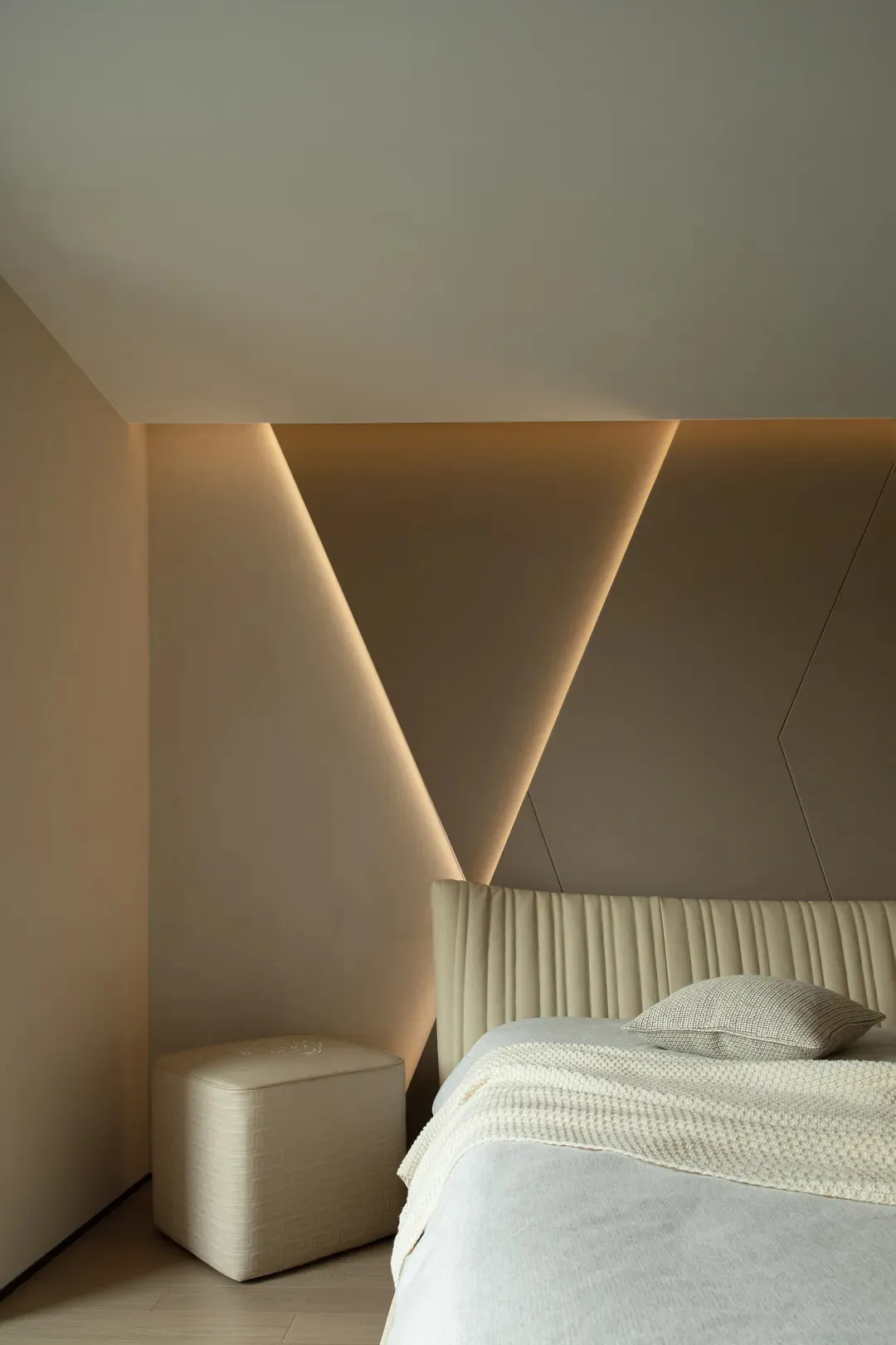 A modern minimalist bedroom featuring a leatherette upholstered bed and geometric lighting fixture