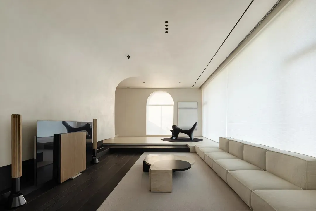 A minimalist living room with a concrete floor, terrazzo table, and a large sofa.