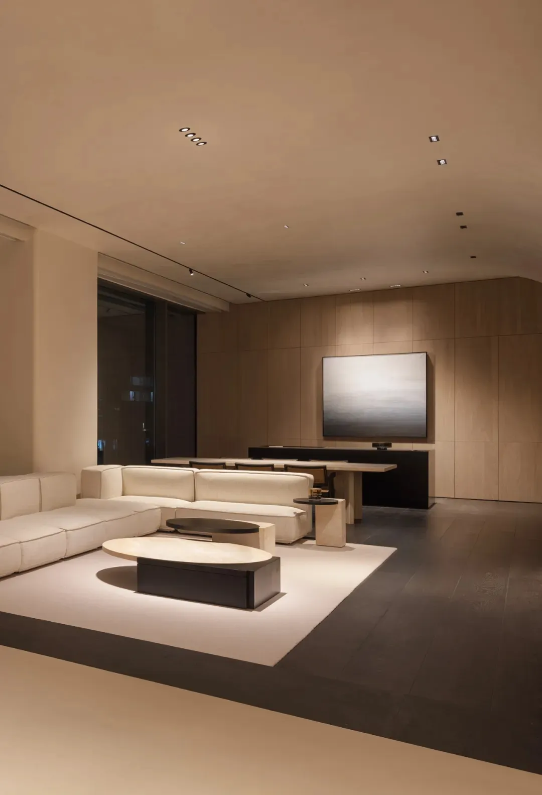Modern minimalist living room with neutral-tones leather furniture and a large screen TV on the wall.