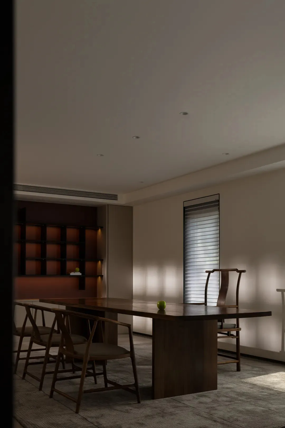 A modern residential dining room featuring a wooden table with chairs and a bookshelf.