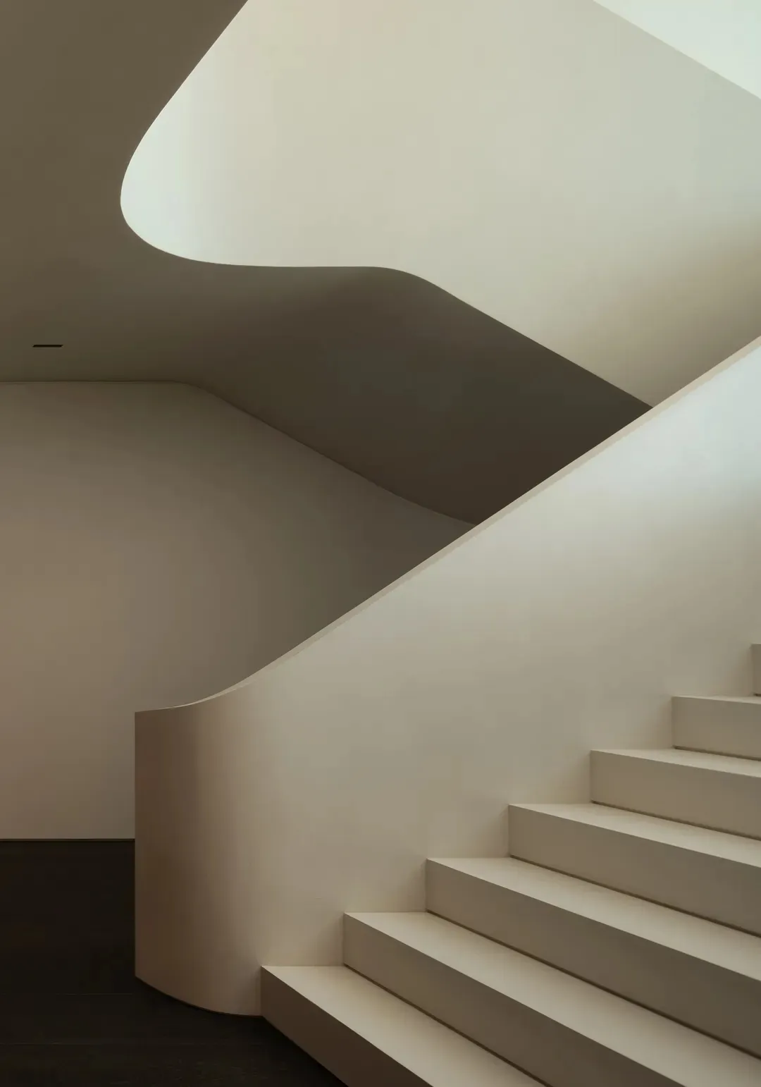 Modern interior design featuring a sleek, white concrete staircase with a curved structure.