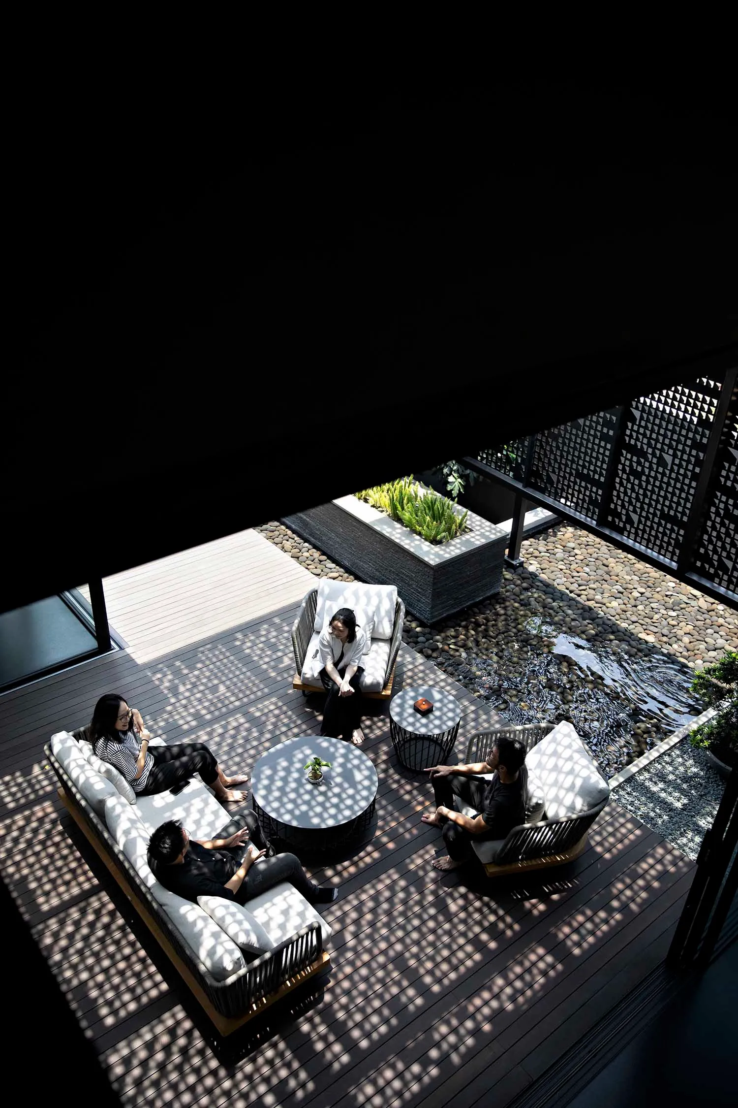People sitting on white and grey cushioned lounge chairs in a modern patio setting.