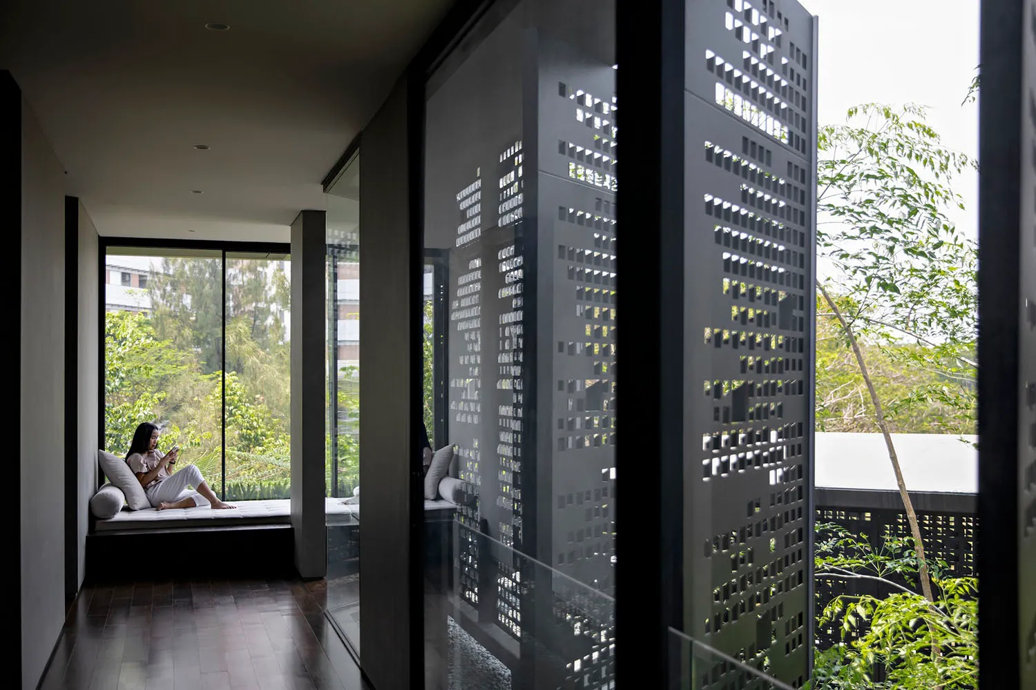 A modern interior space featuring a sleek, geometric steel panel wall, large windows providing natural light, and a serene ou