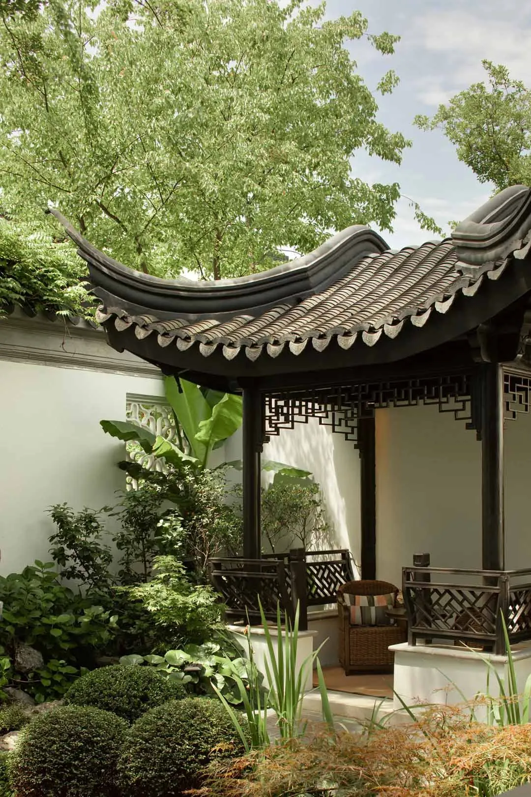A serene Chinese landscape garden featuring a traditional tile-roof gazebo.