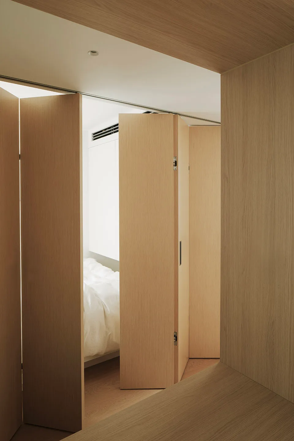 A minimalist bedroom with a wooden platform bed