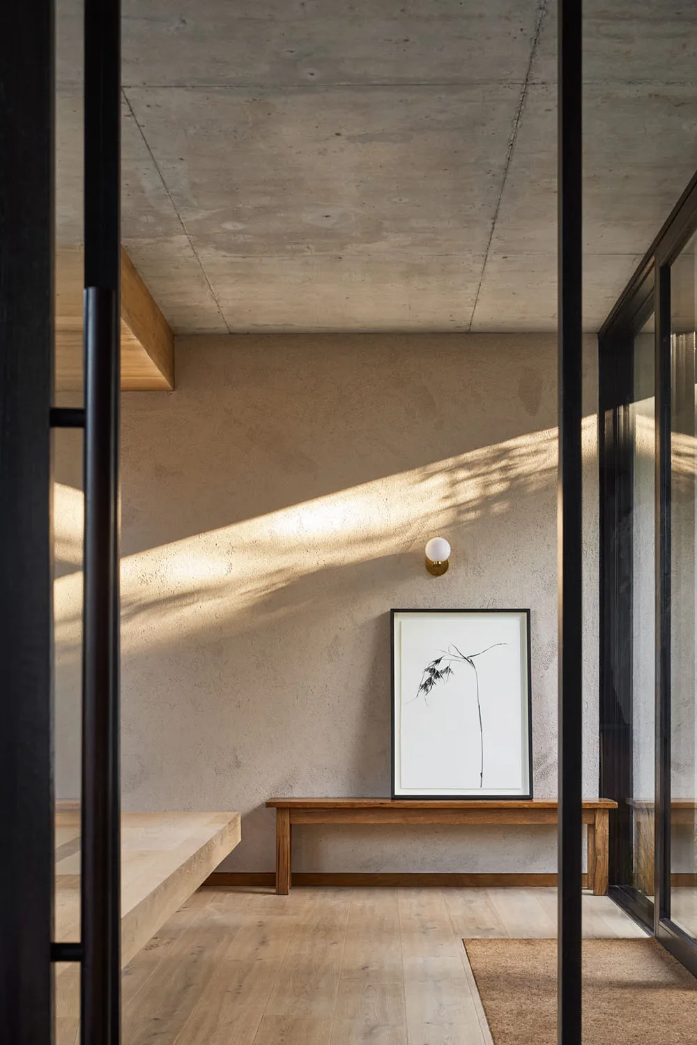 A minimalist interior space featuring concrete walls and wooden furniture.