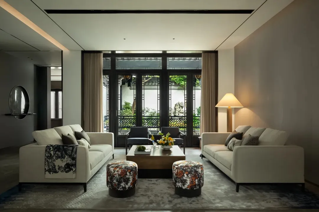 A minimalist living room with neutral tones including white sofas and a wooden coffee table.