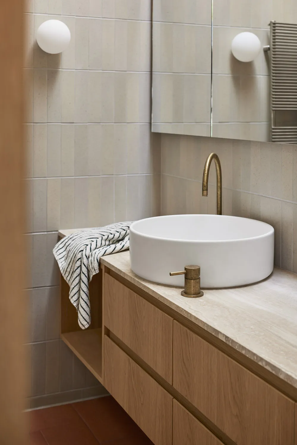 Modern minimalist bathroom with a white vessel sink and a stone countertop.