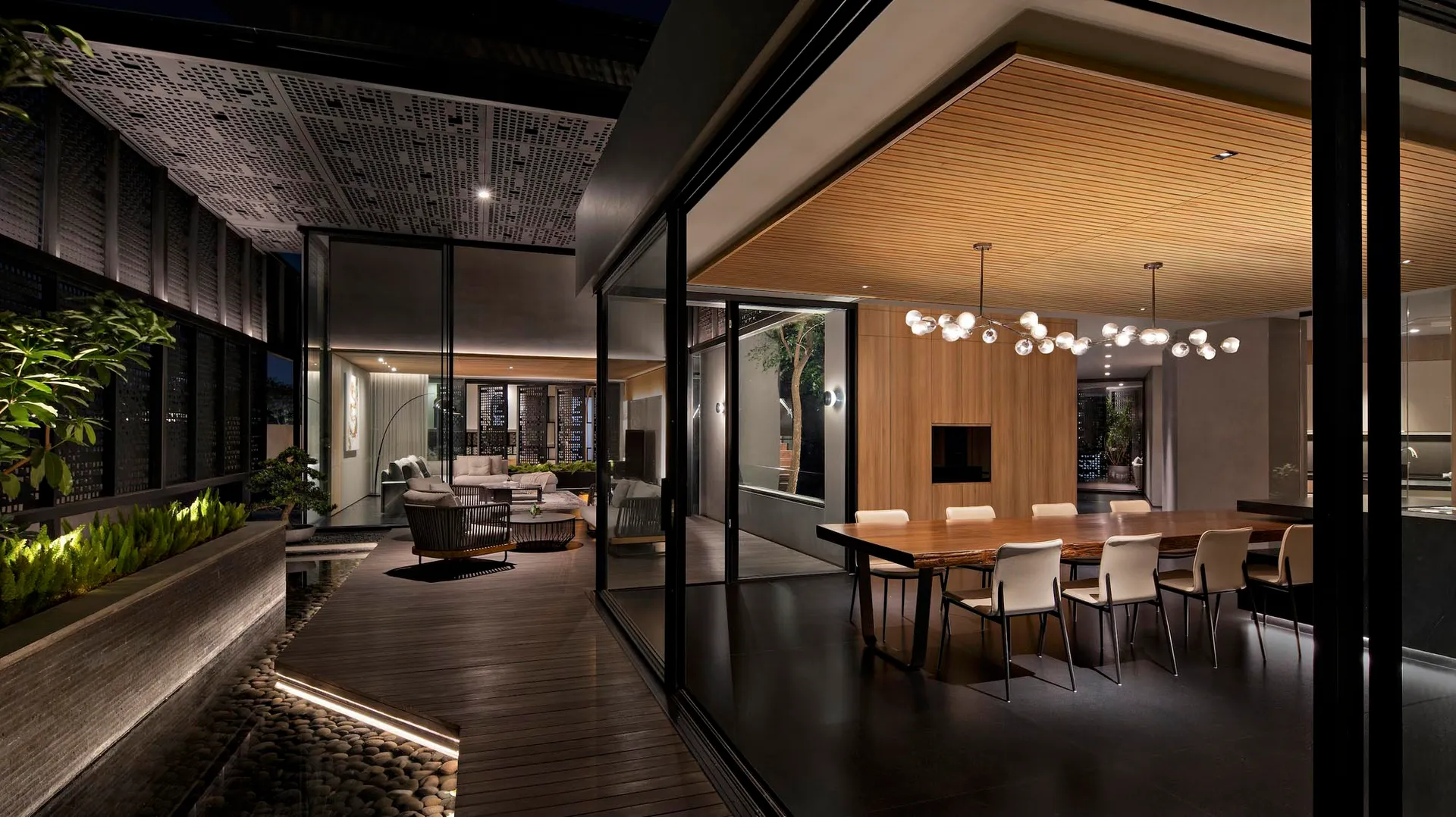 A modern living room with wooden floor and glass walls, featuring a contemporary black and white sofa and a sleek wooden coff